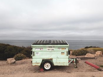 Vintage car on land by sea against sky