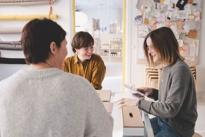 Smiling interior designer discussing with colleagues at desk in workshop