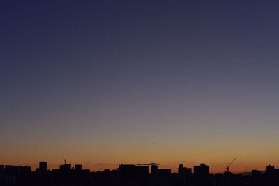 Silhouette city against clear sky during sunset