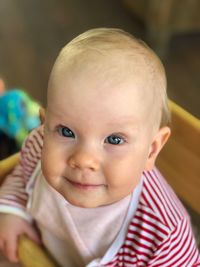 Portrait of cute baby girl sitting on high chair at home