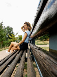 Portrait of woman sitting on footbridge against clear sky