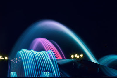 Illuminated ferris wheel against sky at night