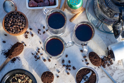 Still life with glass mugs of black hot coffee, coffee beans, making coffee at home