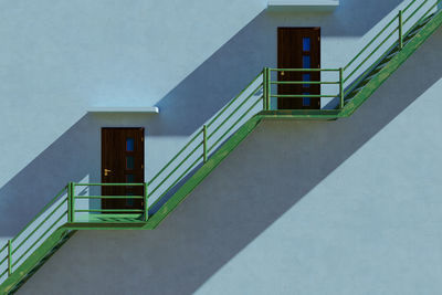 Green iron stairs beside a tall building. light and shadow concept.