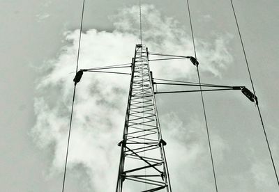 Low angle view of electricity pylon against cloudy sky