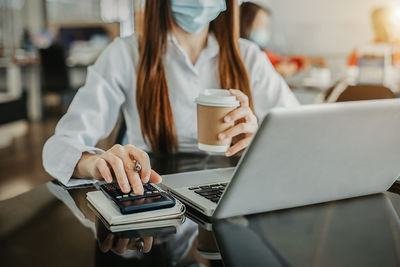 Midsection of woman using laptop at table