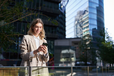 Portrait of young woman standing against buildings