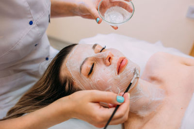 Cosmetologist makes cleansing peeling and face mask for woman. beauty skin care
