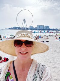 Portrait of woman wearing sunglasses at beach against sky
