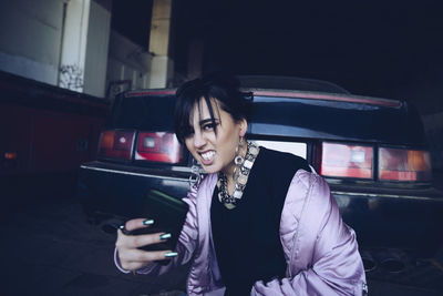 Portrait of young woman taking selfie by car in parking lot