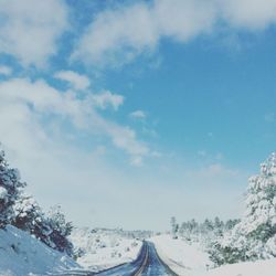 Road amidst snow covered landscape against sky