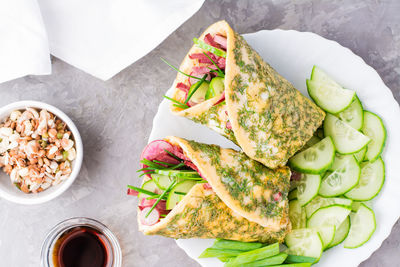 Egg rolls filled with pastrami, vegetables and green onions on a plate, sprouted grains