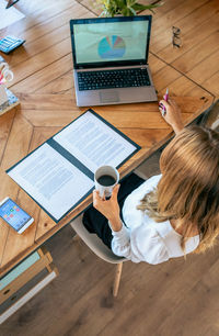 High angle view of woman using mobile phone on table