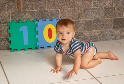 Cute baby boy crawling on floor at home