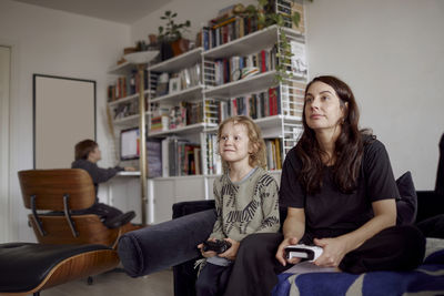 Mother and son playing video games on sofa