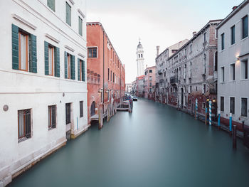 Canal amidst buildings in city against sky