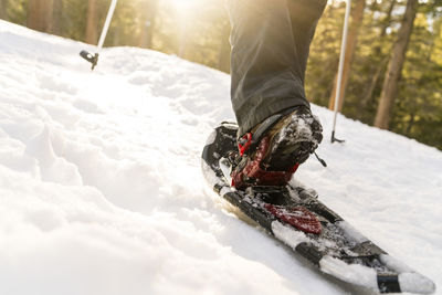 Low section of woman wearing ski while walking on snowy field