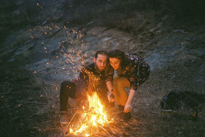 Couple burning campfire at field