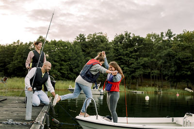 Rear view of people enjoying in lake against sky