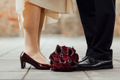 Low section of woman standing on red flower