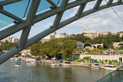 Bridge over river by buildings in city against sky