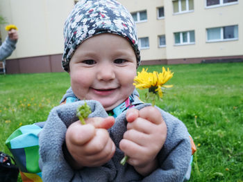 Portrait of a baby showing yellow flowers in his hands