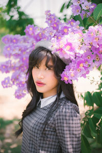 Portrait of woman standing on pink flowering plant