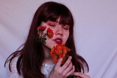 Close-up of beautiful young woman with flowers on cheek