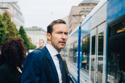 Mature businessman standing by cable car in city