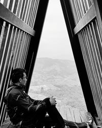 Side view of man looking through window