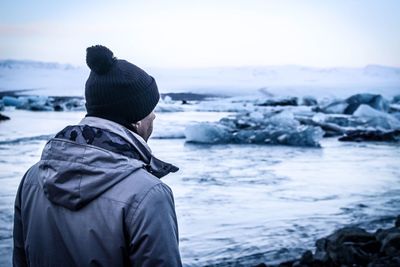 Rear view of couple standing at beach during winter