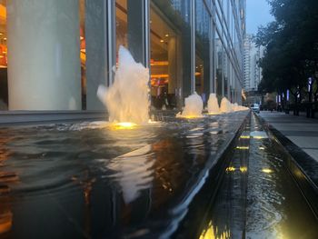 Reflection of illuminated buildings on wet street in city