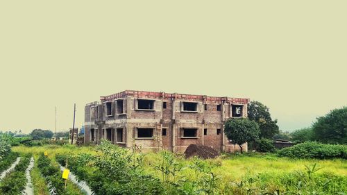 Abandoned house on field against clear sky