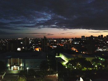 Illuminated cityscape against cloudy sky