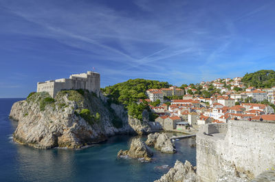 Buildings by sea against blue sky