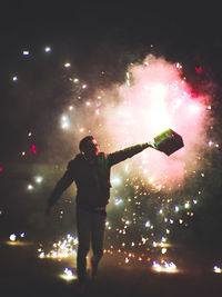 Rear view of man watching firework display at night