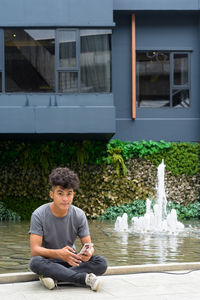 Full length of boy sitting by building