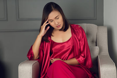 Beautiful young woman sitting on sofa at home