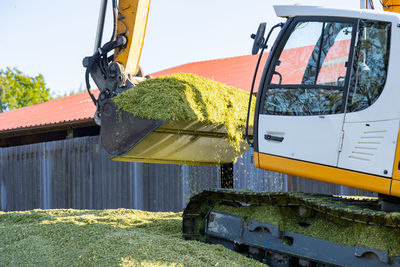 Excavator distributes corn on a corn silage during the corn harvest