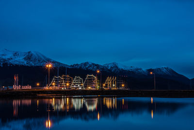 Scenic view of illuminated lake by mountain against sky at night