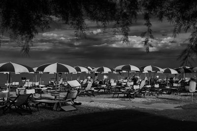 Chairs on beach by sea against sky