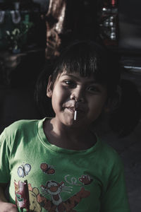 Close-up portrait of girl eating lollipop in darkroom at home