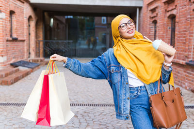 Portrait of young woman standing against building