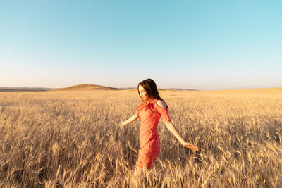 Rear view of woman standing on field against clear sky