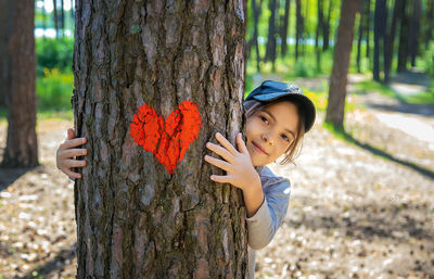 Portrait of cute girl embracing tree trunk