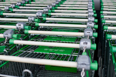 Row of parked trolleys in supermarket. many empty green shopping carts in row.