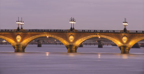 Arch bridge over river at dusk