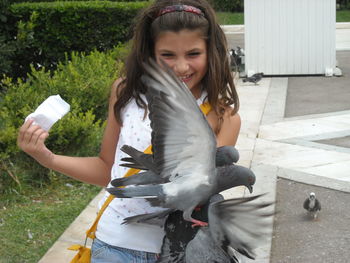 Girl playing with pigeons at park