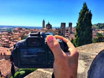 Midsection of woman photographing against clear sky