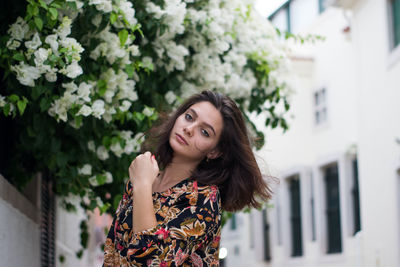 Portrait of beautiful young woman standing against plants